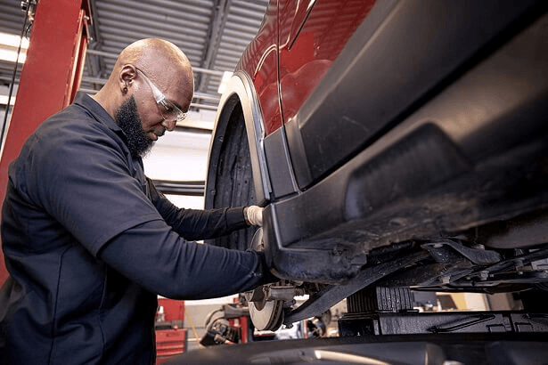 A Meineke technician performing a shocks and struts replacement