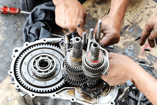 Mechanics working on a Transmission gear box repair in an auto body shop