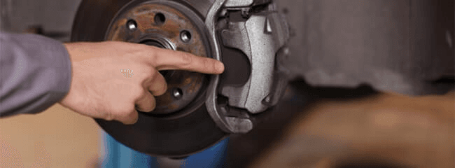 A Technician showing where a Brake pad repair is needed